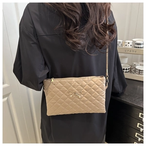 Detailed close-up of khaki quilted crossbody bag with golden bow hardware ornament
