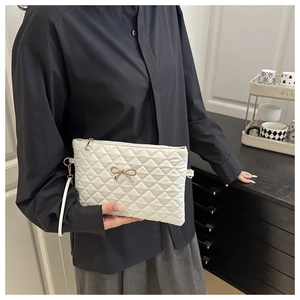 Close-up of white quilted handbag with golden bow detail and soft texture texture