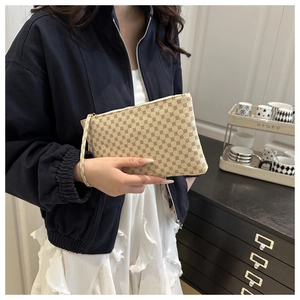 Detail of vintage patterned clutch bag with gold zipper and wrist strap in lifestyle setting