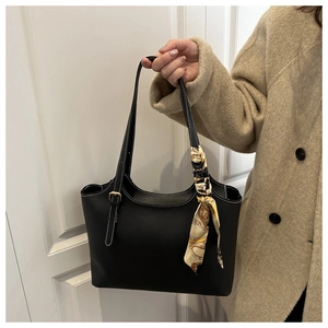 Close-up of black leather tote bag with white contrast stitching and silk scarf decoration