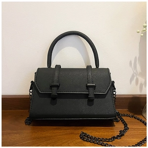 Detail of black cross-grain leather handbag with round handle and dark metal chain strap