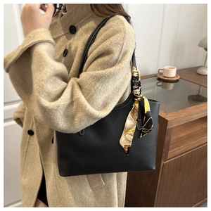 Detail of black leather tote with white stitching and decorative silk scarf on handle