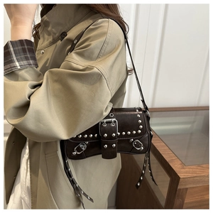 Detail showing silver rivet studs and decorative belt buckle on dark brown leather punk bag