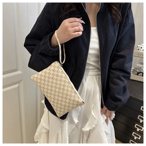 Detail of vintage beige clutch bag with M-letter print and wrist strap held by model