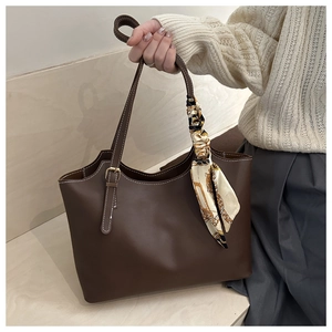 Detail of deep brown leather tote with white stitching and vintage silk scarf accessory