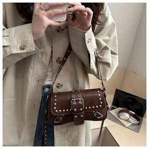 Detail of dark brown vintage crossbody bag with silver studs and wide buckle strap