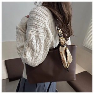 Detail of dark brown leather tote bag with white stitching and vintage print silk scarf