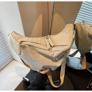 Detail of beige nylon crescent bag featuring braided rope zippers and double compartments