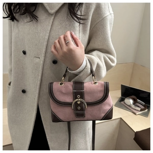 Detail of pink suede and brown leather crossbody bag with golden buckle on model