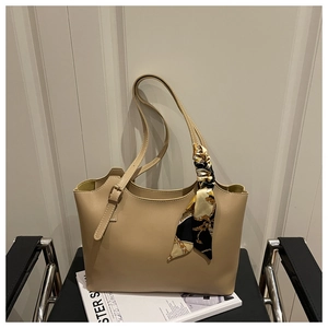 Close-up of beige tote bag with chic printed silk scarf tied on the shoulder strap