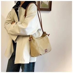 Detail of beige hobo bag with brown leather shoulder strap and side drawstring knots