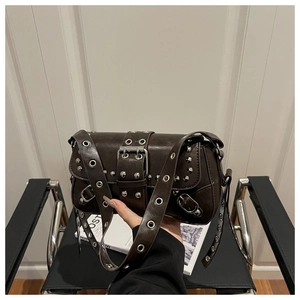 Detail of dark brown punk shoulder bag with silver eyelets and rivets on a designer chair