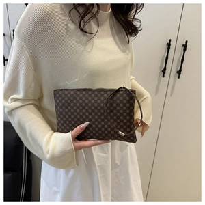 Detail of brown geometric pattern clutch bag held by hand in casual minimalist style