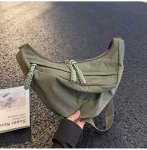 Detail of army green nylon crescent bag featuring two-way zippers and durable woven pullers