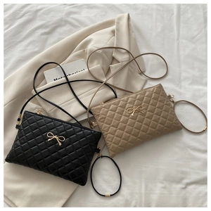 Detailed shot of quilted pattern and gold bow charm on black and khaki shoulder bags