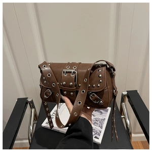 Detail of brown PU leather shoulder bag with silver metal eyelets and rivets decoration