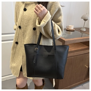 Close-up of a large black PU leather tote bag with decorative straps for daily commuting