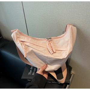 Detailed shot of pink nylon crescent bag featuring braided zipper pullers and long strap