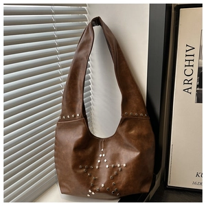 Close-up of vintage brown leather crescent bag with silver rivet star pattern detail