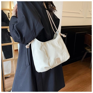 Detail of creamy white crescent shoulder bag with vertical stitching and drawstring balls