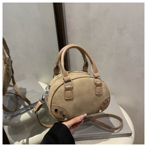 Dettaglio borsa bowling in camoscio beige con borchie argentate e manici in pelle