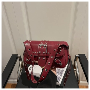 Close-up of wine red punk shoulder bag with silver grommets and rivet detailing