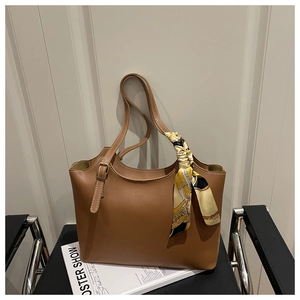 Detailed view of a brown tote bag featuring a decorative printed silk scarf and metal hardware