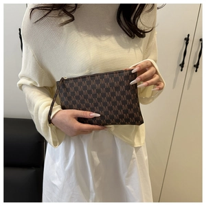 Close-up of vintage brown patterned envelope clutch bag with golden zipper and strap