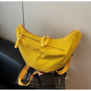 Detail of bright yellow nylon crescent bag featuring dual zippers and woven knot pulls