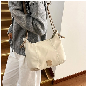 Detail of a minimalist cream white crossbody bag featuring a brown leather Fashion logo
