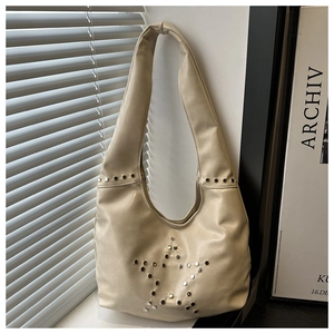 Macro detail of creamy white crescent bag with silver star rivet patterns and soft leather