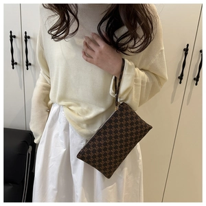 Detail of brown patterned wristlet clutch with M print and secure zipper closure