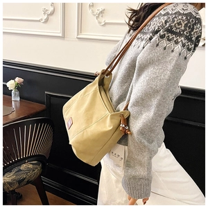 Detail of khaki single shoulder bag with side drawstring and brown leather brand label