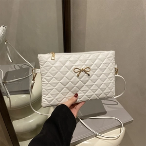 Quilted white crossbody bag with golden metal bow accent and elegant leather strap