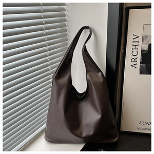 Detail of dark brown leather tote bag showing soft texture and natural draping folds