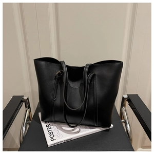 Detail of a black leather tote bag featuring golden adjustable buckle and sleek straps