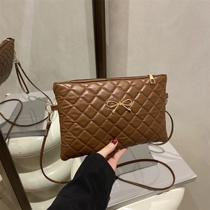Quilted crossbody bag in brown leather with a gold metal bow and thin strap
