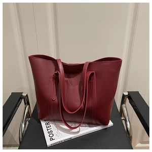 Close-up of a large burgundy PU leather tote bag placed on a magazine for daily use