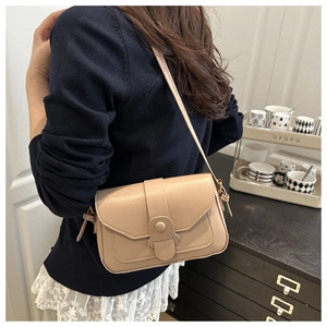 Detail of apricot crossbody bag showing decorative strap and round buckle closure