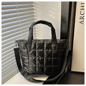 Detailed close-up of quilted black puffer tote bag with adjustable nylon shoulder strap
