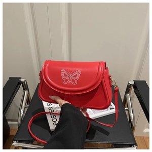 Detailaufnahme der weißen Schmetterlingsstickerei auf einer roten Lederschultertasche