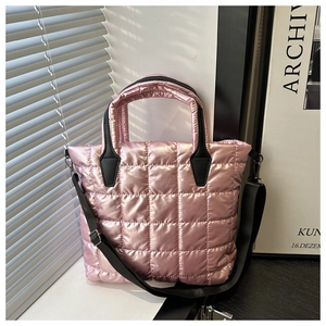 Detail of pink metallic quilted bag with black handles and square stitching texture