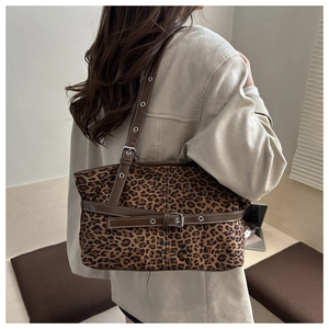 Detail of leopard print shoulder bag with brown leather strap and metal eyelet buckles