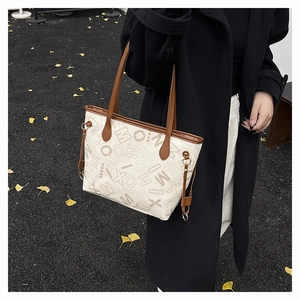 Détail du sac cabas crème avec imprimé lettres et finitions en cuir marron élégant