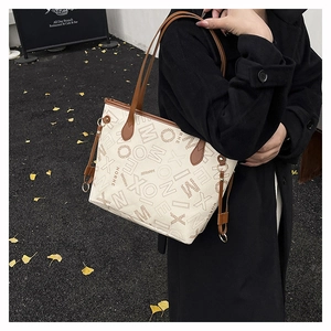 Photo de sac cabas crème avec imprimé lettres brunes et lanières en cuir porté par modèle