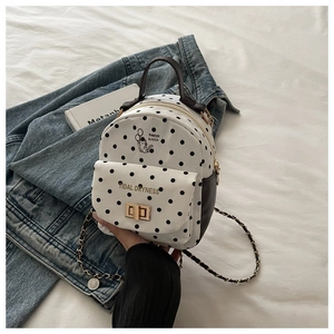 Détail du mini sac à dos en toile blanche à pois noirs avec boucle en métal doré