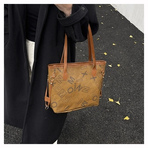 Détail du sac cabas en cuir marron avec imprimé lettres et boucle métallique latérale