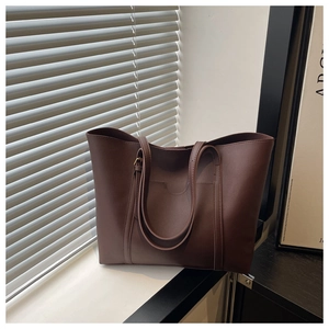 Detailed close-up of dark brown leather tote bag with exterior pocket and matte texture