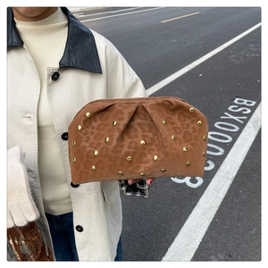 Close-up of leopard print dumpling clutch bag with golden rivets held by a model