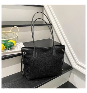 Detail view of large black fleece tote bag with side metal rings and drawstring accents